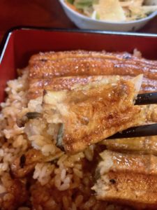 割烹川松駅前店の鰻とご飯を箸で持ってみた写真