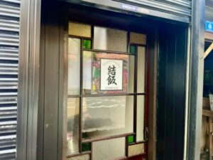 市川駅南口近くにある居酒屋食堂 結飯の入口と店舗ロゴ（2026年4月28日筆者撮影）