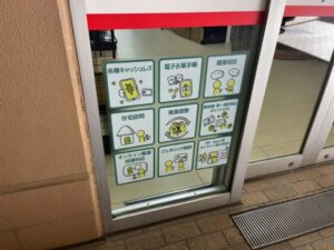 くすりの福太郎 市川南口2号店の入口ガラス掲示。電子お薬手帳や健康相談、在宅訪問、オンライン受付などの対応案内（2026年2月28日筆者撮影）