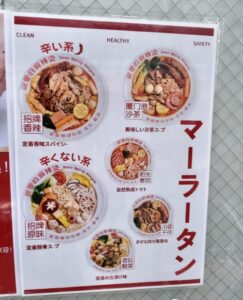親愛の麻辣湯（マーラータン）南行徳駅前店の店頭に掲示されたメニュー例（辛い系・辛くない系、沙茶スープ、トマト、四川風干拌、酸菜などの味の種類）2026年2月25日筆者撮影