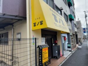冨ノ家（トミノヤ）外観｜黄色い看板と入口周辺の様子（本八幡・八幡本店）2026年3月4日筆者撮影