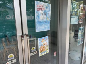 ワンルーク千葉市川店の入口ドアに掲示されたオープン告知とペットホテル案内ポスター（2026年4月23日筆者撮影）