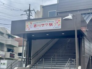 市川真間駅の駅舎上部に設置された「市川ママ駅」看板（2026ね4月30日筆者撮影）