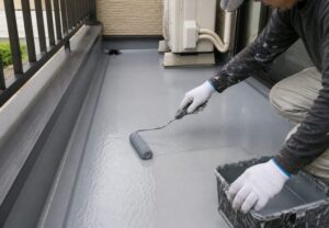 ベランダの床面に防水塗料を塗り広げているバルコニー防水工事のイメージ